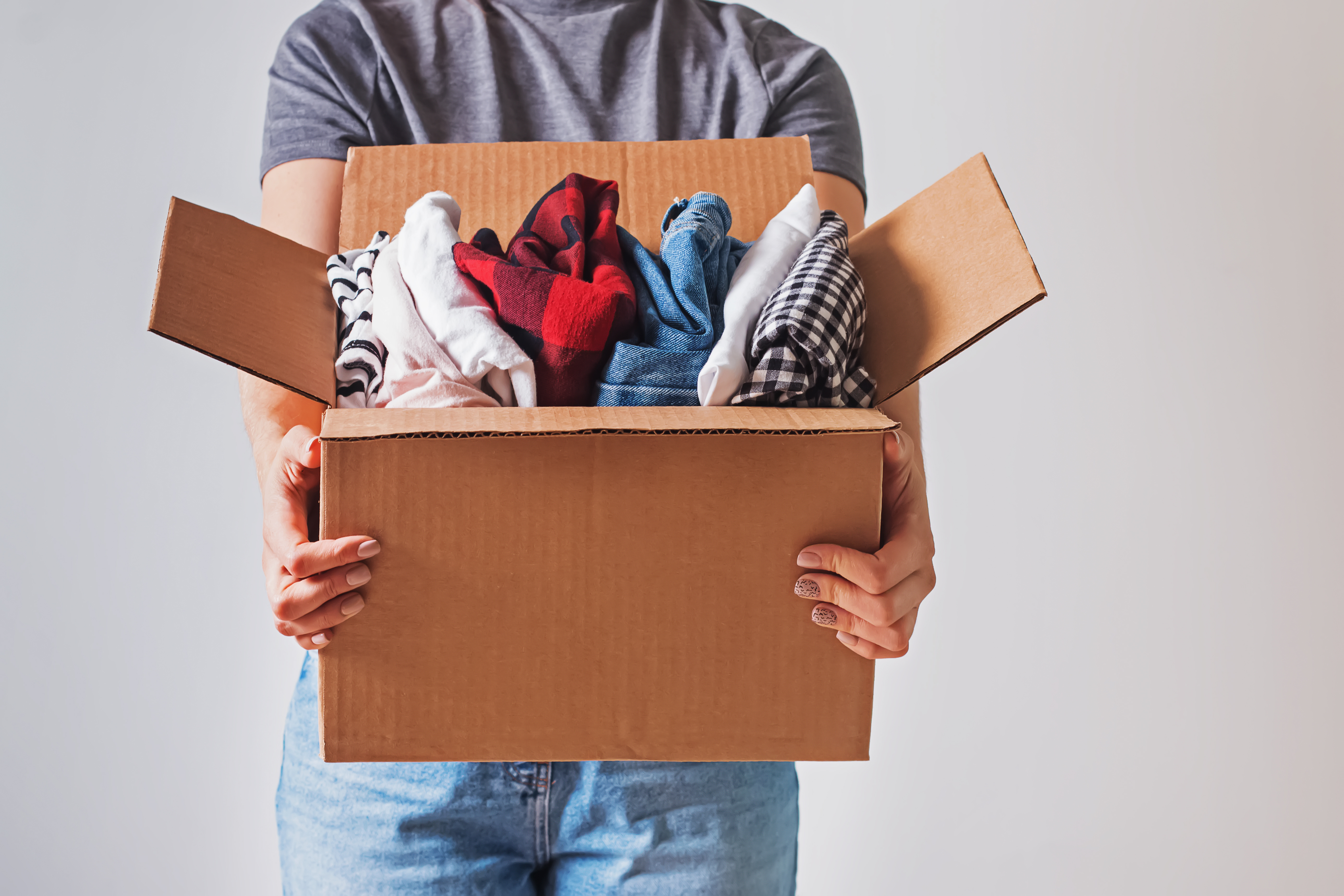 Unrecognizable woman holding box with clothes in it. close-up.